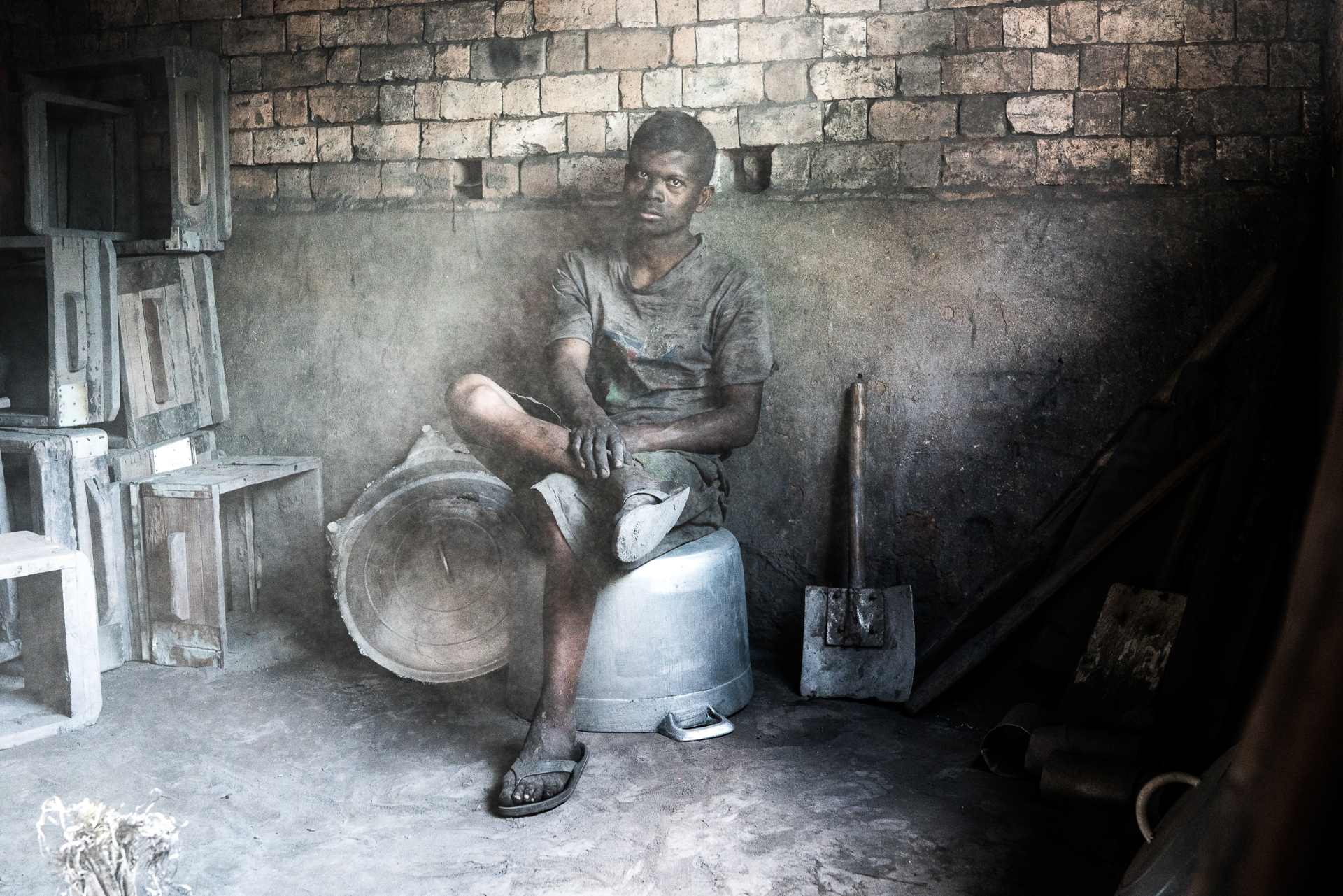 Portrait photo d'un travailleur assis dans une fonderie d'aluminium à Madgascar par Lucas Dumortier