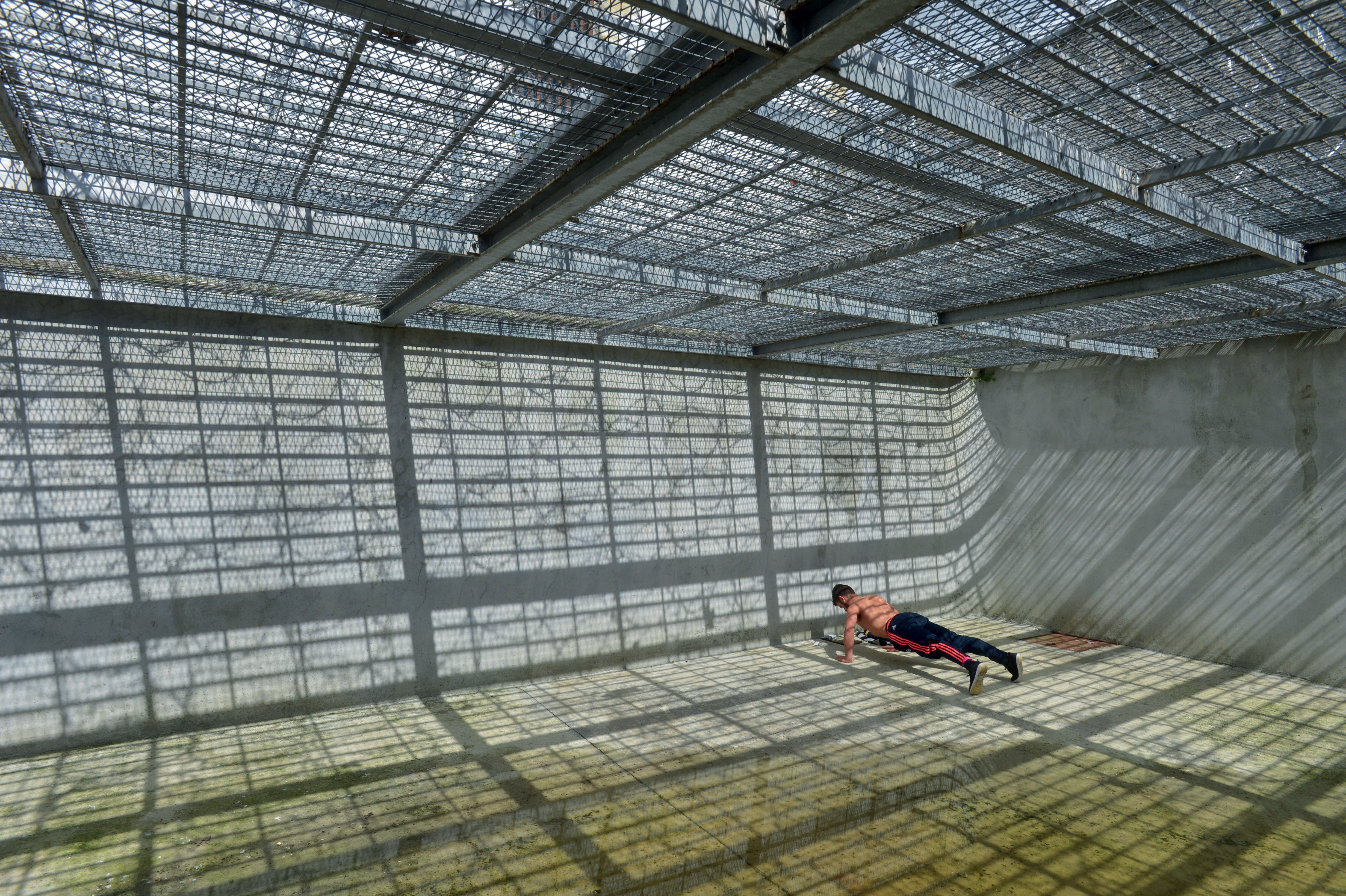 Photographie d'un homme faisant des pompes enfermé dans une prison par Jean-Christophe Hanché