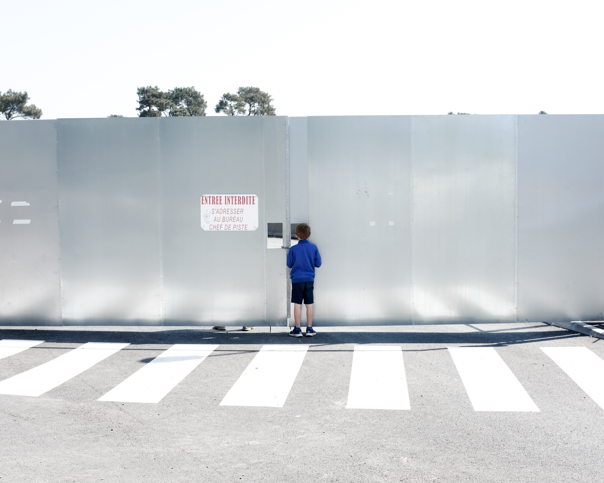Image d'un enfant regardant par le trou d'une porte le circuit des 24h Auto du Mans par Aurélien Delafond