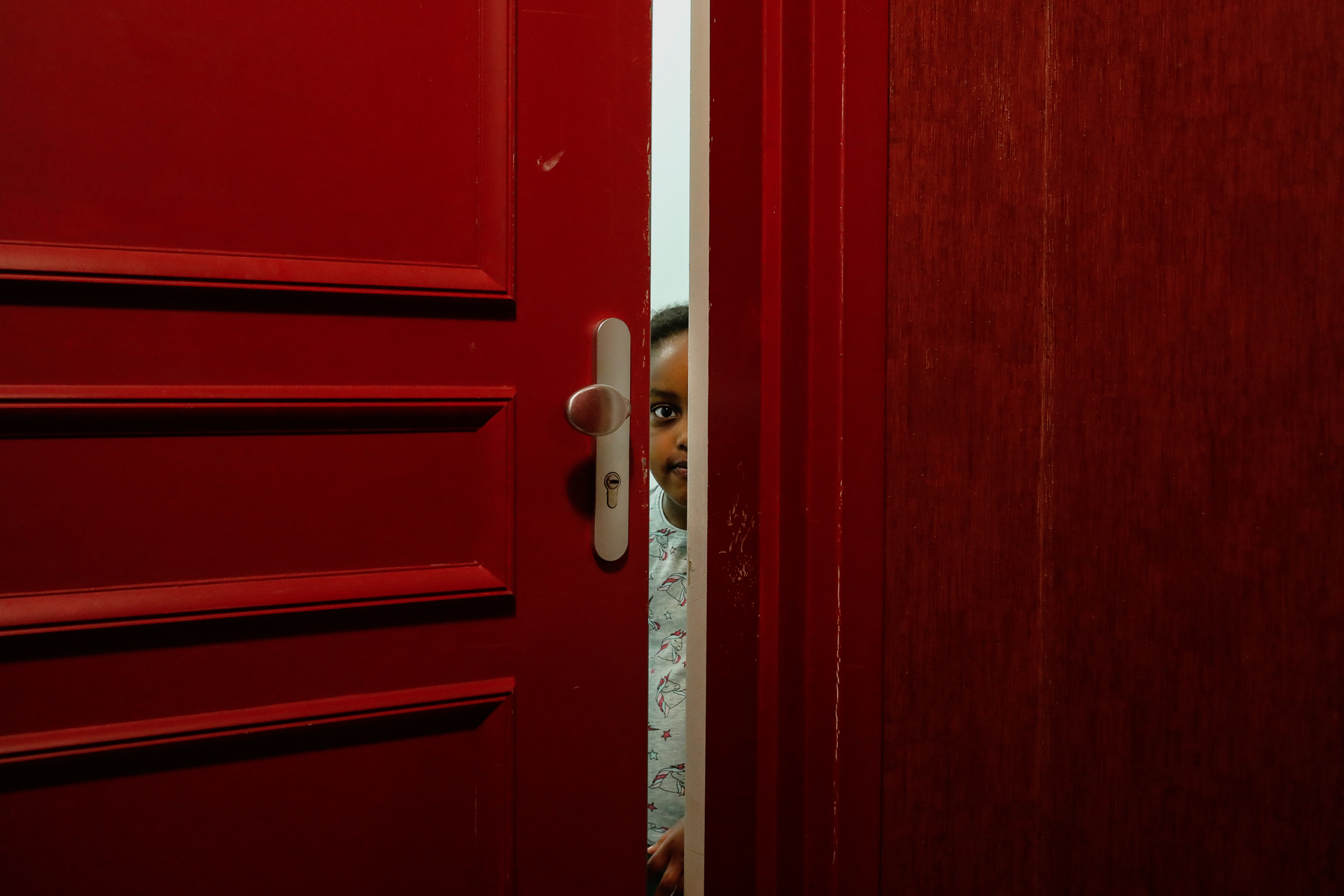 Image d'une porte entrouverte qui laisse apparaitre le visage d'un enfant par Anouk Desury, Covid 19