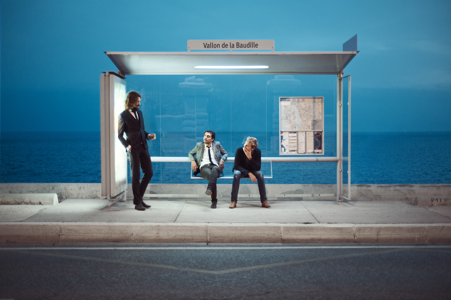Photo de trois hommes assis à un arrêt de bus au bord de la mer à Marseille par Bertrand Jamot