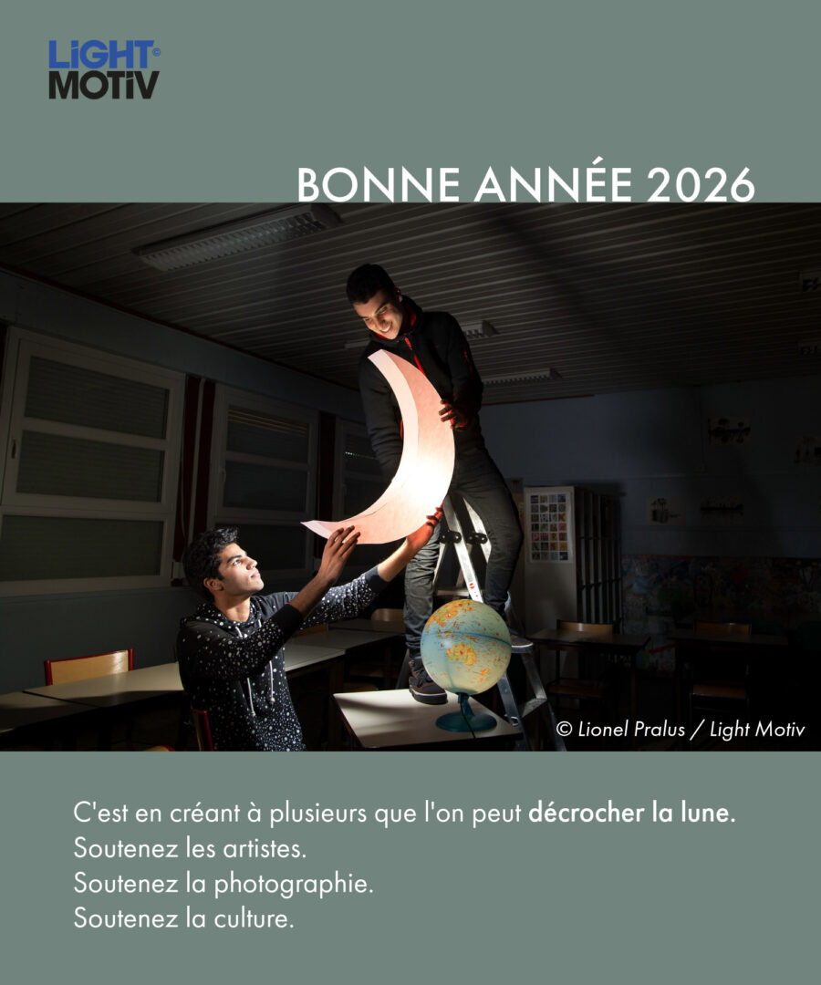 Visuel de voeux de la nouvelle année 2026 par l'agence photographique Light Motiv, avec une photographie issue de la série de Lionel Pralus représentant deux jeunes hommes décrochant un croissant de lune illuminé dans une salle de classe. Un texte est ajouté sous l'image : "C'est en créant à plusieurs que l'on peut décrocher la lune. Soutenez les artistes. Soutenez la photographie. Soutenez la culture."