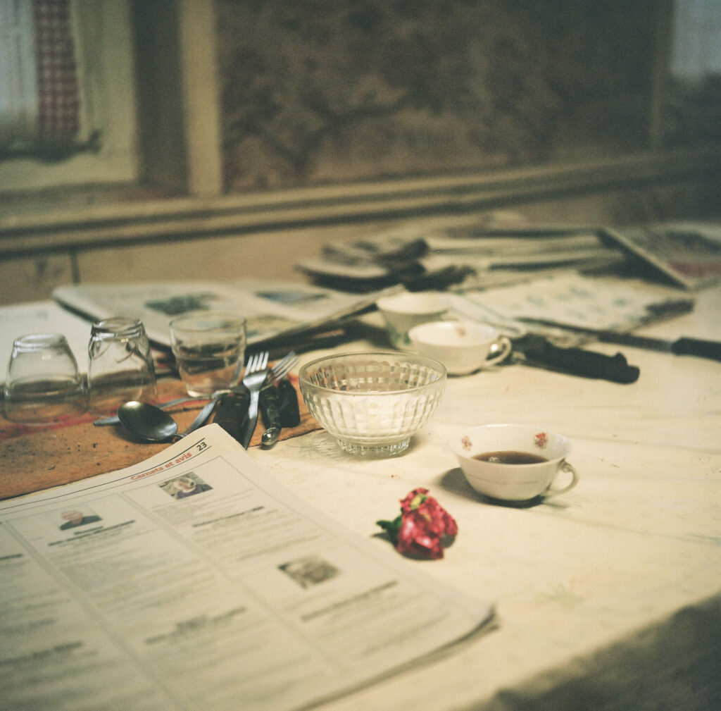 Photographie de Zélie Hallosserie / Light Motiv, issue de la série intitulé Jean Marie, représentant une table sur laquelle est disposé divers objets tels que des tasses, bols, verres et couverts, dans l'intention de capturer les moments de vie d'un homme appelé Jean Marie.