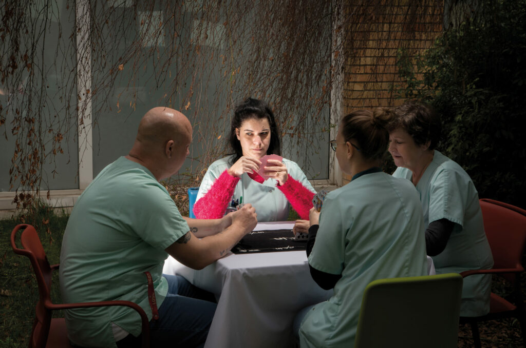Photographie de Lionel Pralus / Light Motiv, issue de la série intitulée Désordre Ordinaire datant de 2020, représentant un groupe de quatres personnes autour d'une table en train de jouer à un jeu de cartes, dans le cadre d'un projet tourné autour de mise en scène photographiques avec les patients et professionnels du SAAS.