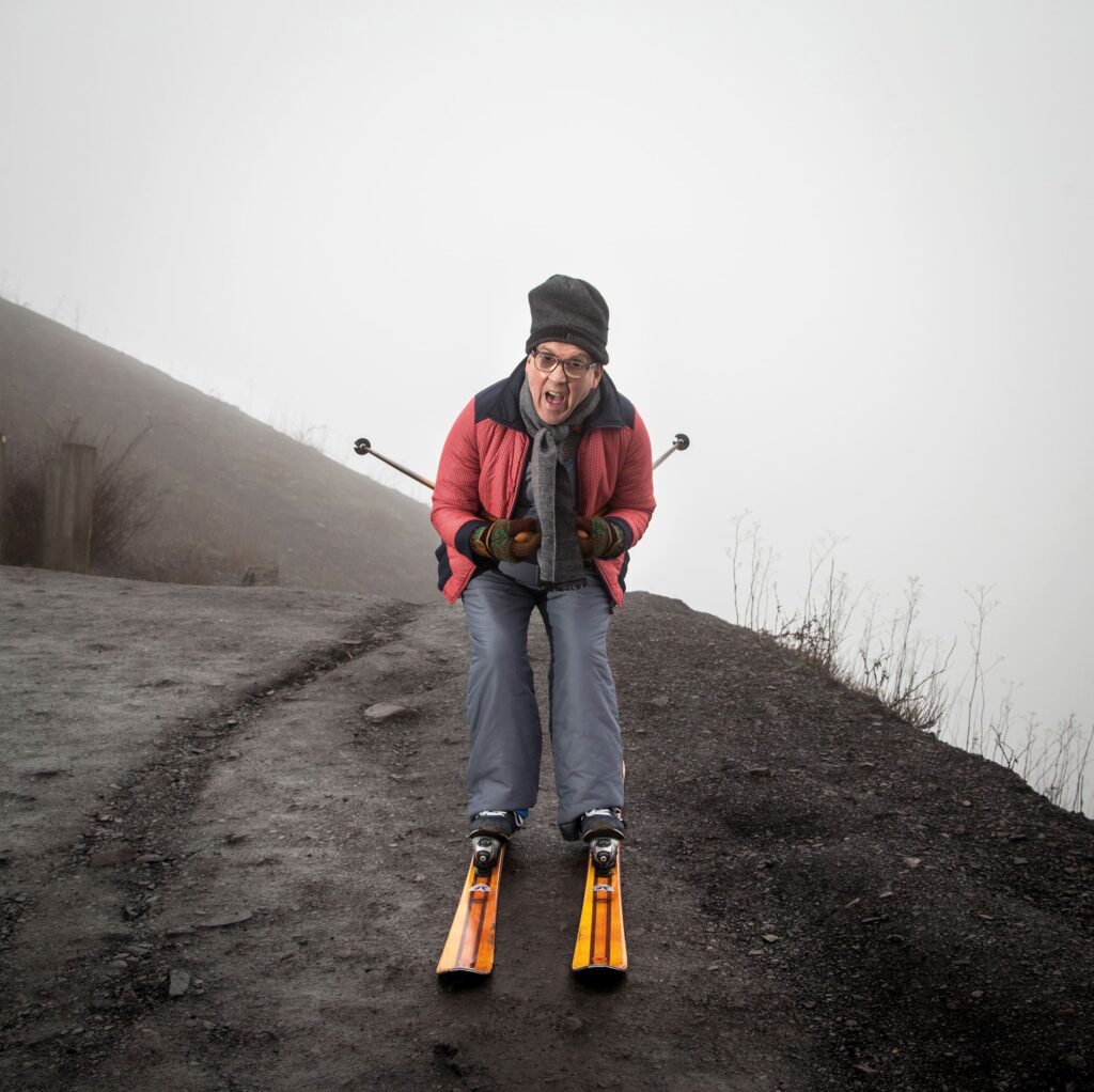 Photographie de Lionel Pralus / Light Motiv, issue de la série intitulée Désordre Ordinaire datant de 2020, représentant un homme en ski sur une montagne noire fonçant droit vers la caméra en ayant une expression déterminée, dans le cadre d'un projet tourné autour de mise en scène photographiques avec les patients et professionnels du SAAS.