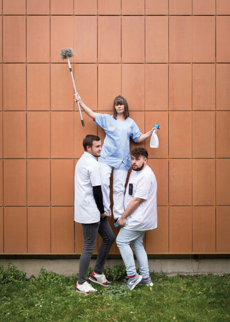 Photographie de Lionel Pralus / Light Motiv, issue de la série intitulée Désordre Ordinaire datant de 2020, représentant une femme soulevée en l'air par deux hommes, dans le cadre d'un projet tourné autour de mise en scène photographiques avec les patients et professionnels du SAAS.