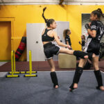 Photographie d'Anouk Desury / Light Motiv issue de sa série Les Poings Ouverts, représentant la jeune boxeuse Shaïna en plein entraînement, lançant un coup de pied à une adversaire.